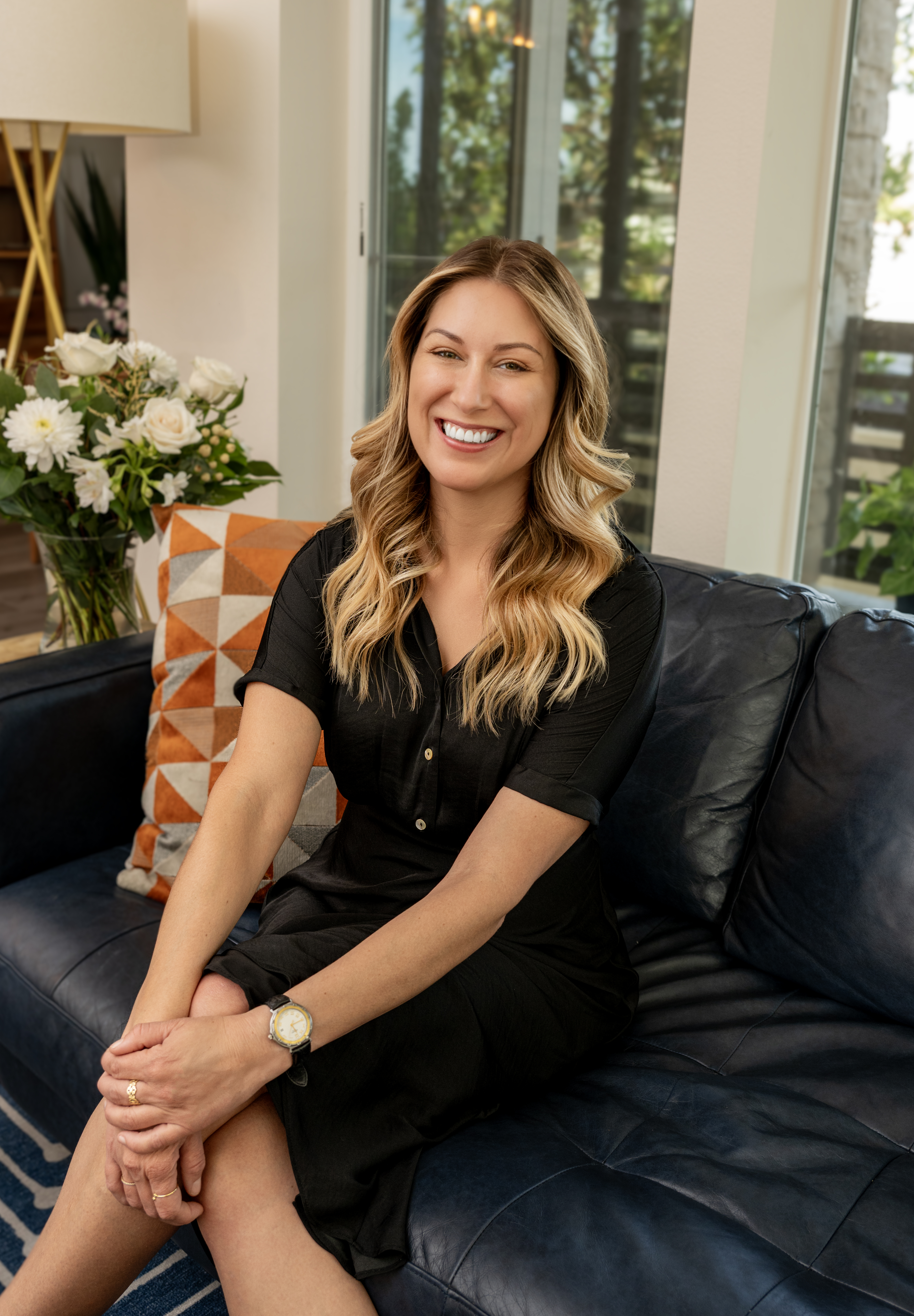 Share Holland, smiling, seated on a navy leather sofa